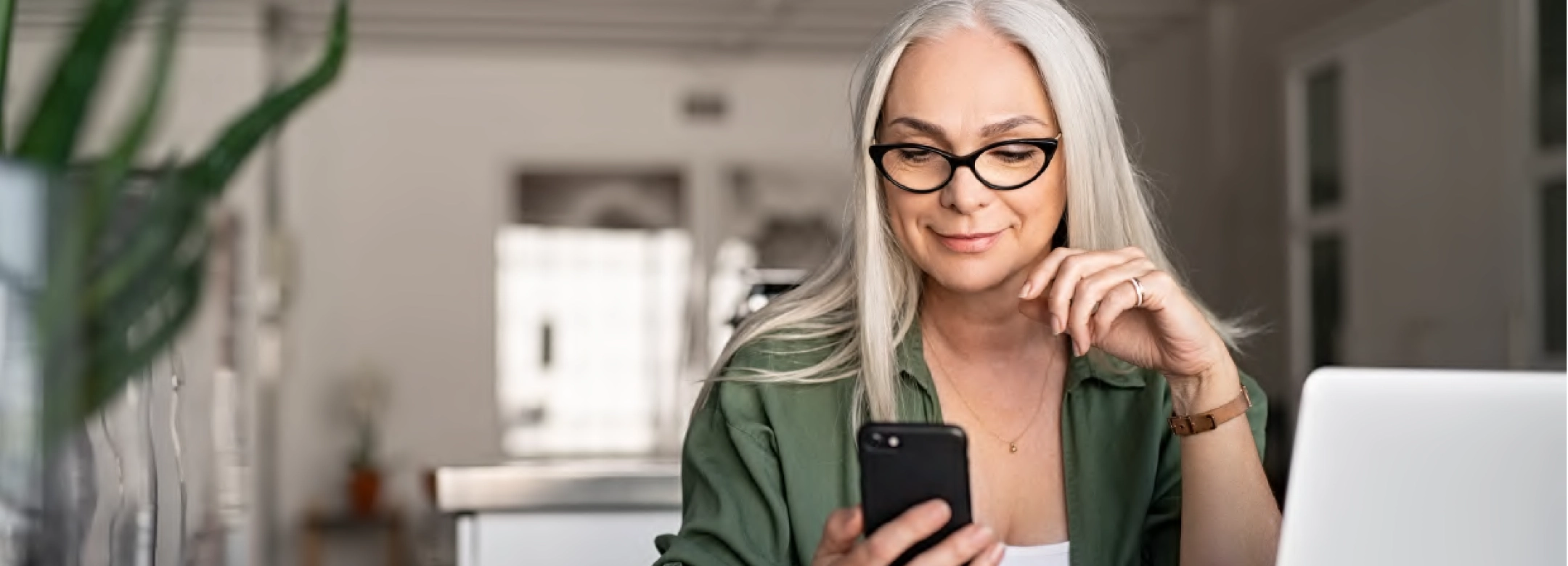 Woman sat at computer using phone