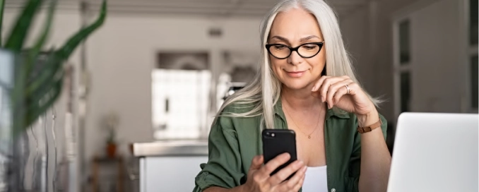 Woman sat at computer using phone